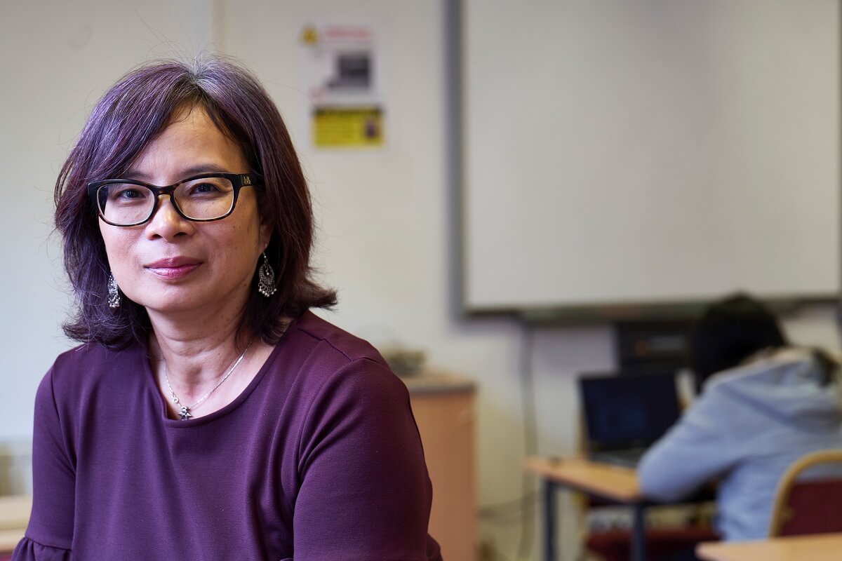 Older Asian female teacher in classroom with background out of focus