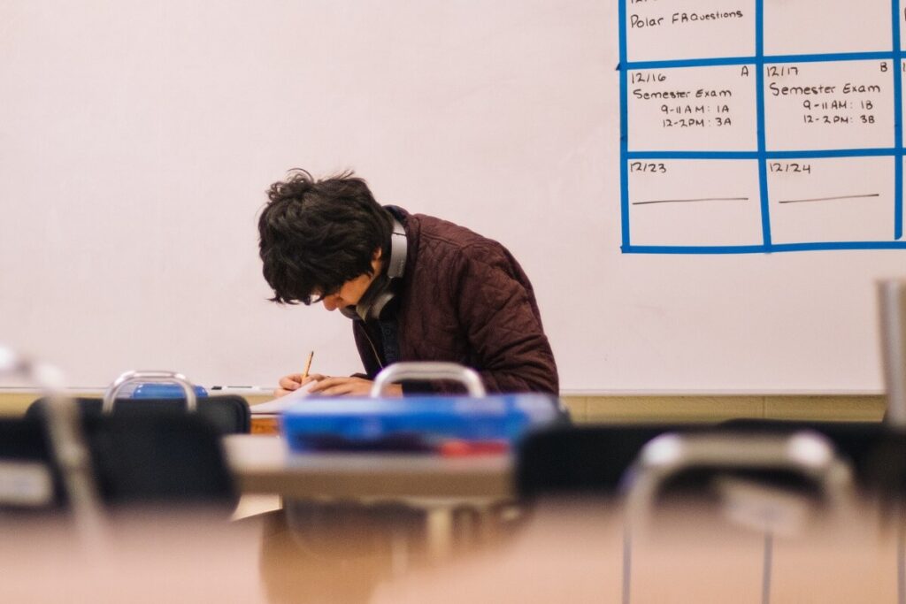 Older student with headphones working on homework alone in classroom