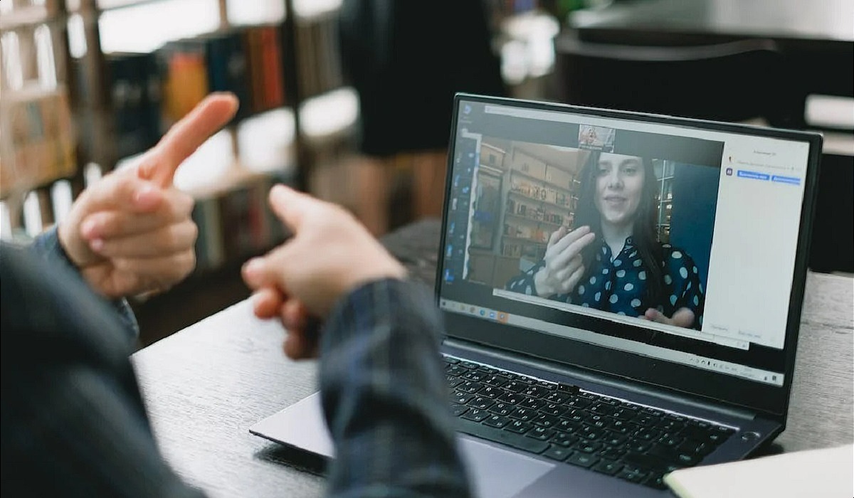 Young lady learning sign language during online lesson with female tutor