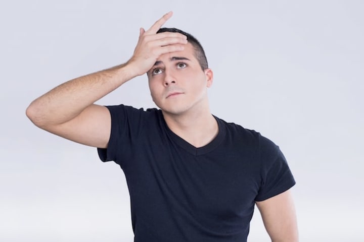 Man with hand on forehead trying to remember something