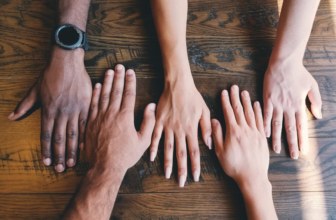 Group of hands laying on wooden table