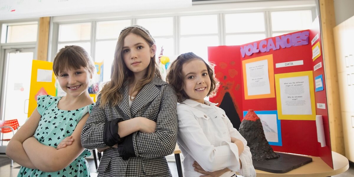 confident school girls with arms crossed at science fair