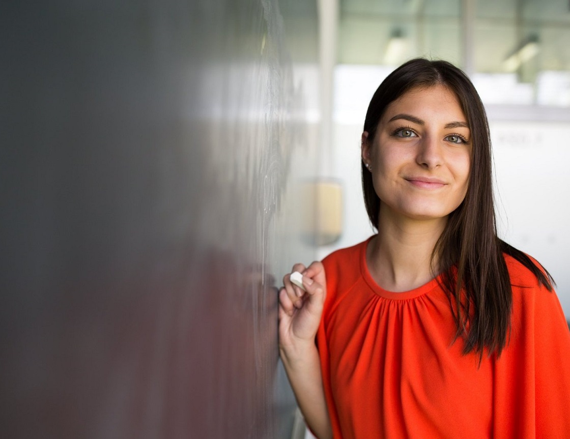 Woman in red smiling and leaning against reflective wall