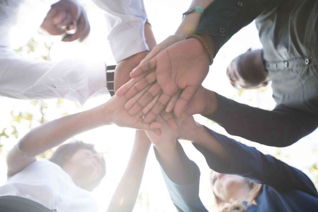 Group of people in a circle placing their hands on top of each other