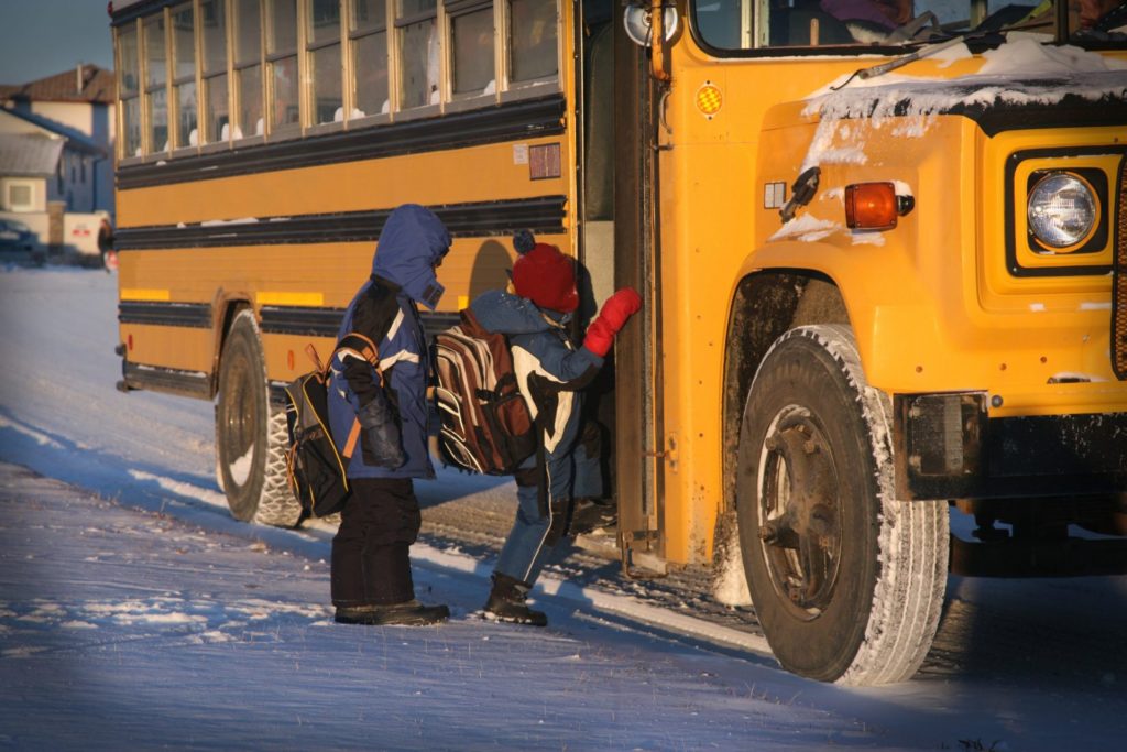 Boys boarding school bus in the snow