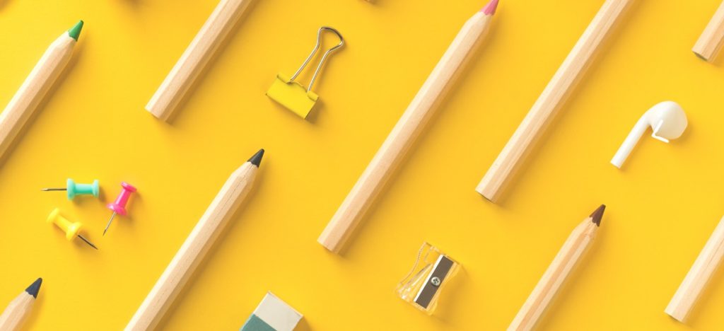 Colored pencils and office supplies on a yellow background