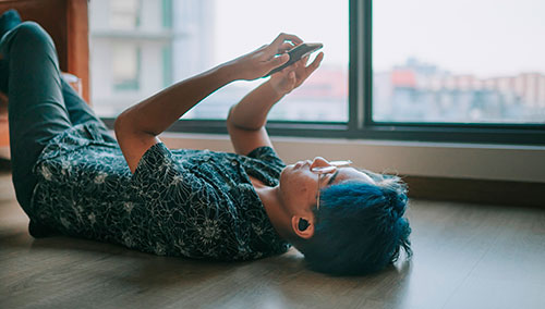 Teen on floor looking at smartphone