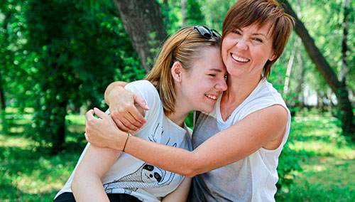 Female friends hugging and laughing in nature