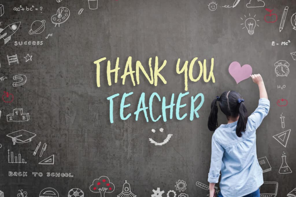 Girl student writes Thank You Teacher and doodles on chalkboard