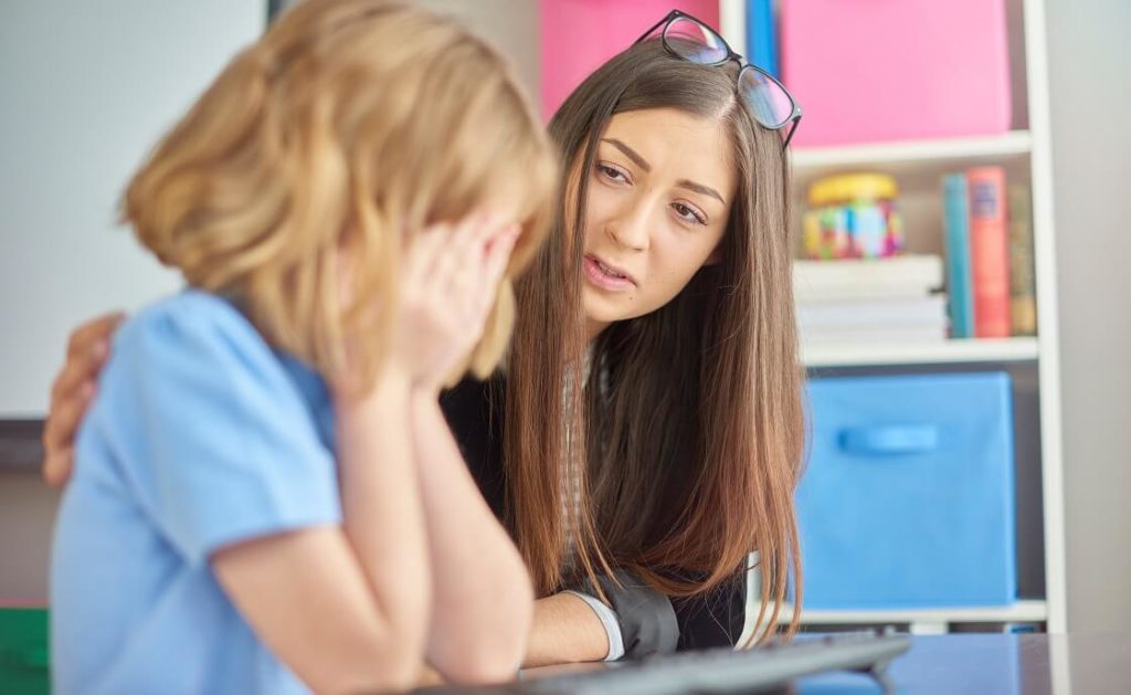 Teacher consulting crying grade school student