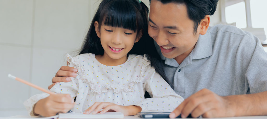 Asian father helping daughter with homework in notebook