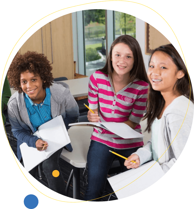 African American boy and two girl middle school students laughing in class with notebooks