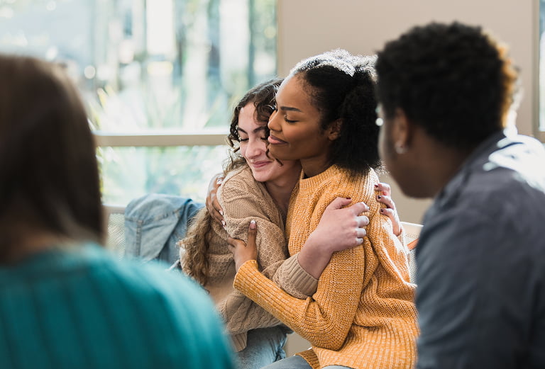 friends hug and comfort each other after being vulnerable with their group