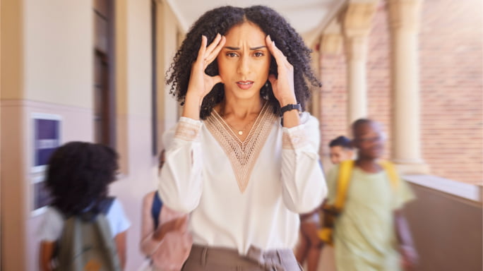 Black female teacher stressed in blurred school hallway