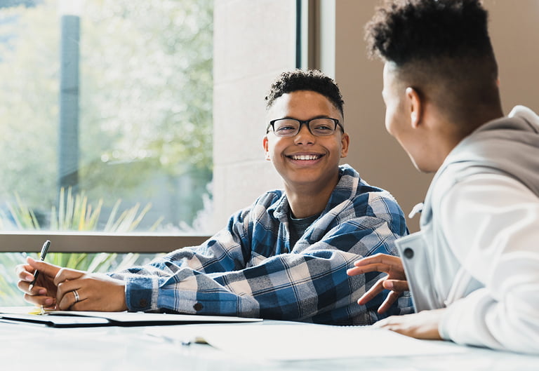 teenage boy smiles listening to his friend tell a story before class