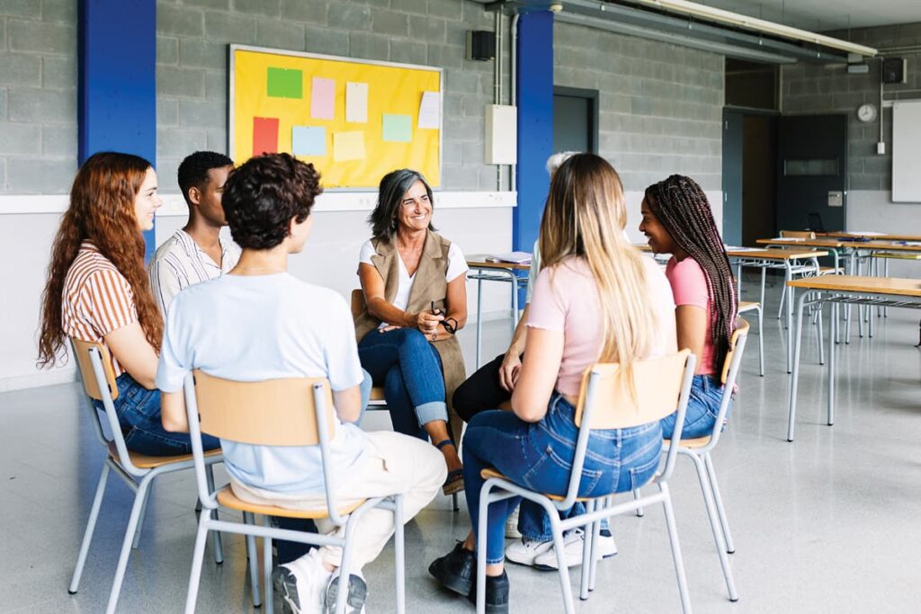 Teacher and students sitting on chairs in circle
