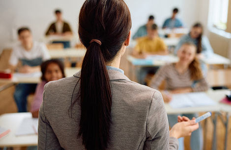 Back of female teacher giving lecture in high school classroom