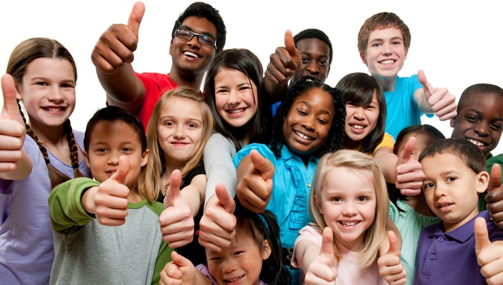 Group of diverse K-12 children standing together giving thumbs up
